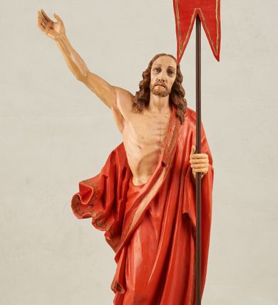 Zdjęcie nr 1: Figura pełnoplastyczna, ustawiona na niewysokim, prostopadłościennym postumencie o ściętych narożach. Chrystus przedstawiony całopostaciowo, frontalnie, w lekkim kontrapoście. Głowa nieznacznie uniesiona do góry, prawa ręką wyciągnięta ku górze, lewa wsparta na drzewcu chorągwi Zmartwychwstania. Twarz Zbawiciela szczupła, wydłużona o wyraźnych rysach. Duże, głęboko osadzone, szeroko otwarte oczy skierowane są ku górze. Wydatny, prosty nos oraz delikatnie zaznaczone czerwienią usta. Długie, brązowe włosy opadające w lokach na ramiona i plecy postaci. Na twarzy widoczny krótki, brązowy zarost. Odsłonięta klatka piersiowa z wyraźnie zaznaczoną muskulaturą oraz widoczną raną w boku. Na lewe ramię postaci luźno zarzucony obszerny, czerwony płaszcz ze złotą lamówką. Spod szat widoczne bose stopy. Czerwona chorągiew na długim, brązowym drzewcu zakończonym krzyżem. Figura w pełni polichromowana.