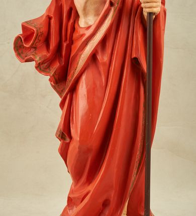 Zdjęcie nr 12: Figura pełnoplastyczna, ustawiona na niewysokim, prostopadłościennym postumencie o ściętych narożach. Chrystus przedstawiony całopostaciowo, frontalnie, w lekkim kontrapoście. Głowa nieznacznie uniesiona do góry, prawa ręką wyciągnięta ku górze, lewa wsparta na drzewcu chorągwi Zmartwychwstania. Twarz Zbawiciela szczupła, wydłużona o wyraźnych rysach. Duże, głęboko osadzone, szeroko otwarte oczy skierowane są ku górze. Wydatny, prosty nos oraz delikatnie zaznaczone czerwienią usta. Długie, brązowe włosy opadające w lokach na ramiona i plecy postaci. Na twarzy widoczny krótki, brązowy zarost. Odsłonięta klatka piersiowa z wyraźnie zaznaczoną muskulaturą oraz widoczną raną w boku. Na lewe ramię postaci luźno zarzucony obszerny, czerwony płaszcz ze złotą lamówką. Spod szat widoczne bose stopy. Czerwona chorągiew na długim, brązowym drzewcu zakończonym krzyżem. Figura w pełni polichromowana.