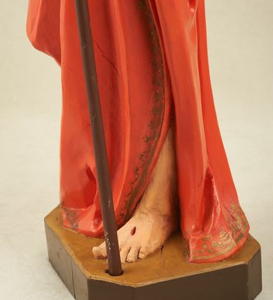 Zdjęcie nr 4: Figura pełnoplastyczna, ustawiona na niewysokim, prostopadłościennym postumencie o ściętych narożach. Chrystus przedstawiony całopostaciowo, frontalnie, w lekkim kontrapoście. Głowa nieznacznie uniesiona do góry, prawa ręką wyciągnięta ku górze, lewa wsparta na drzewcu chorągwi Zmartwychwstania. Twarz Zbawiciela szczupła, wydłużona o wyraźnych rysach. Duże, głęboko osadzone, szeroko otwarte oczy skierowane są ku górze. Wydatny, prosty nos oraz delikatnie zaznaczone czerwienią usta. Długie, brązowe włosy opadające w lokach na ramiona i plecy postaci. Na twarzy widoczny krótki, brązowy zarost. Odsłonięta klatka piersiowa z wyraźnie zaznaczoną muskulaturą oraz widoczną raną w boku. Na lewe ramię postaci luźno zarzucony obszerny, czerwony płaszcz ze złotą lamówką. Spod szat widoczne bose stopy. Czerwona chorągiew na długim, brązowym drzewcu zakończonym krzyżem. Figura w pełni polichromowana.