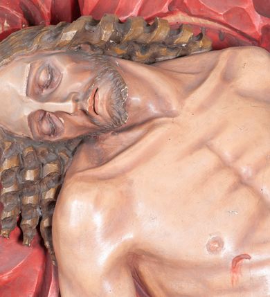 Zdjęcie nr 12: Rzeźba ustawiona na niewysokim, prostopadłościennym postumencie oraz na konsoli w kształcie fragmentu pilastra o kanelowanym trzonie i kapitelu dekorowanego motywem wolich oczu. Na tle krzyża z luźno przewieszoną przez poziomą belkę białą tkaniną ukazani Maria oraz martwy Chrystus. Jezus o szczupłym, muskularnym ciele z widocznymi śladami męki ukazany w pozycji półleżącej z torsem i ramionami wspartymi o postać Marii. Ręce ułożone luźno wzdłuż ciała. Głowa Chrystusa opada na prawe ramię postaci; twarz szczupła z wyraźnie zarysowanymi kośćmi policzkowymi, oczy zamknięte. Długie, brązowe włosy z przedziałkiem pośrodku głowy skręcają się w spiralne loki. Na twarzy krótki zarost. Wokół bioder Chrystusa luźno owinięte białe perizonium. Maria ukazana w pozycji klęczącej z rękoma uniesionymi na boki w dynamicznym geście. Głowa pochylona nieznacznie do dołu, w kierunku ciała Chrystusa. Twarz Marii szczupła, owalna z głęboko osadzonymi, dużymi oczami oraz wydatnym, prostym nosem. Postać ubrana jest w czerwoną suknię z długimi rękawami, niebieski płaszcz oraz białą chustę z podwiką wokół szyi. Po lewej stronie kompozycji, spod sukni widoczna jest bosa stopa.  