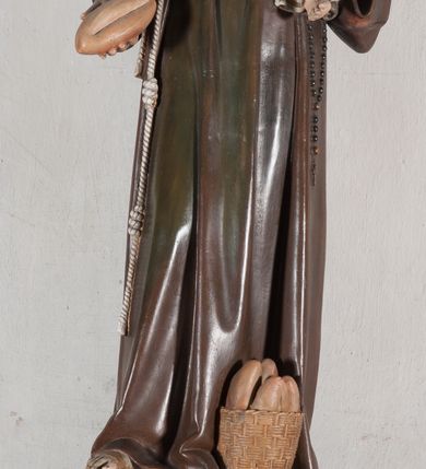 Zdjęcie nr 1: Rzeźba pełnoplastyczna, umieszczona na niewielkim prostopadłościennym postumencie o ściętych narożach oraz złoconej i srebrzonej konsoli utworzonej z liści akantu i róż. Święty ukazany całopostaciowo, frontalnie w pozycji stojącej. Antoni został przedstawiony jako młody mężczyzna o owalnej, pozbawionej zarostu twarzy i krótkich, brązowych włosach z tonsurą. Ma oczy wpatrzone przed siebie, wydatny, prosty nos, usta zamknięte. Postać w prawej ręce trzyma bochenek chleba, a na lewej podtrzymuje Dzieciątko Jezus. Święty ubrany jest w długi, ciemnobrązowy habit franciszkański. Do sznura z trzema węzłami ujmującego go w pasie przywiązany jest różaniec. Spod habitu widoczne stopy obute w sandały. U stóp ustawiony kosz z bochenkami chleba. Jasnowłose Dzieciątko Jezus ukazane w pozycji siedzącej z głową zwróconą w trzech czwartych w prawo. Prawą ręką wykonuje gest błogosławieństwa, lewą składa na piersi, podtrzymując kwiat białej lilii. Postać ubrana z białą tunikę ze złotą lamówką wokół dekoltu, rękawów oraz dolnej krawędzi szaty. Na konsoli, na której ustawiona jest rzeźba widnieje napis: ŚWIĘTY ANTONI MÓDL SIĘ ZA NAMI.
