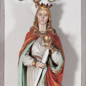 Zdjęcie nr 1: Rzeźba drążona, ustawiona na niewielkim, prostopadłościennym postumencie o ściętych narożach oraz rozbudowanej, neobarokowej konsoli. Święta ukazana frontalnie, w pozycji stojącej z kielichem w lewej dłoni i mieczem w prawej. Barbara została przedstawiona jako młoda, jasnowłosa kobieta o owalnej twarzy, dużych, niebieskich oczach i wydatnym nosie. Ubrana jest w strój królewski złożony z długiej, białej sukni ze złotymi elementami oraz czerwonego płaszcza z seledynowym podbiciem. Płaszcz jest spięty pod szyją ozdobną, złotą broszą. Na głowie postaci złota, wysadzana kamieniami szlachetnymi korona w typie otwartym. U jej stóp z lewej strony przedstawiona owalna wieża zwieńczona krenelażem. Konsola, na której ustawiona jest rzeźba wspierana jest przez postać jasnowłosego anioła w niebieskiej szacie trzymającego w rękach banderolę z napisem „Św(ięta) BARBARO Módl się za nami”. Anioł umieszczony na tle srebrzonego obłoku; banderola, skrzydła anioła oraz detale architektoniczne konsoli złocone.