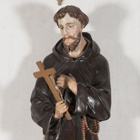 Zdjęcie nr 1: Rzeźba pełnoplastyczna, umieszczona na niewielkim prostopadłościennym postumencie o ściętych narożach oraz złoconej i srebrzonej konsoli utworzonej z liści akantu i róż. Święty ukazany całopostaciowo, frontalnie w pozycji stojącej. Franciszek został przedstawiony jako dojrzały mężczyzna o podłużnej, szczupłej twarzy i krótkich, brązowych włosach i brodzie. Ma duże, ciemne oczy wpatrzone przed siebie, wydatny ostro zakończony nos, usta zamknięte. Postać w prawej ręce trzyma krucyfiks, a lewą dłoń składa na piersi. Święty ubrany jest w długi, ciemnobrązowy habit franciszkański. Do sznura z trzema węzłami ujmującego go w pasie przywiązany jest różaniec. Spod habitu widoczne stopy obute w sandały. Na podstawie, na której ustawiona jest rzeźba widnieje napis „Św(ięty) FRANCISZEK”, na konsoli „ŚWIĘTY FRANCISZKU MÓDL SIĘ ZA NAMI”.