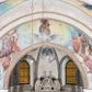 Zdjęcie nr 1: Prezbiterium: 
Sklepienie krzyżowo-żebrowe, dwuprzęsłowe. Pola sklepienne malowane są na kolor beżowy. Od strony wschodniej z centralnie umieszczonymi trzema kolistymi medalionami, mieszczącymi przedstawienie gołębicy Ducha Świętego w obłokach na błękitnym tle (w medalionie centralnym) oraz przeciwstawnie ustawione popiersia dwóch serafinów przedstawionych jako jasnowłosi młodzieńcy w pastelowych szatach, z nimbem wokół głowy (w medalionach skrajnych). W ścianach tarczowych umieszczone wizerunki czterech ewangelistów wraz z ich atrybutami. W pierwszym od wschodu przęśle przedstawienie św. Jana z orłem (po lewej od ołtarza) i św. Mateusza z aniołem (po prawej). W przęśle drugim wizerunek św. Łukasza z uskrzydlonym bykiem (po lewej) i św. Marka z uskrzydlonym lwem (po prawej). Ewangeliści ukazani w popiersiu, na tle błękitnego nieba, obłoków i promienistego nimbu. W dolnej części każdej z kompozycji przedstawione symbole każdego z ewangelistów. Święty Jan ukazany jako młody, jasnowłosy mężczyzna z głową zwróconą w prawo. Ubrany jest w jasnozieloną szatę oraz luźno przerzucony przez ramię różowy płaszcz. W prawym ręku trzyma pióro, w lewym księgę. Świętego Mateusza przedstawiono jako starszego, siwowłosego i brodatego mężczyznę z głową zwróconą w lewo. Ubrany jest w złotą szatę oraz błękitny płaszcz. Swoją lewą rękę składa na piersi, prawą wskazuje w dół. Święty Łukasz przedstawiony jest jako starszy siwowłosy i brodaty mężczyzna ukazany w dynamicznej pozie – z głową z profilu zwróconą w lewo oraz lewą ręką uniesioną do góry. Postać ubrana jest w jasnofioletową szatę oraz błękitny płaszcz. Świętego Marka przedstawiono z ciałem zwróconym w trzech czwartych w prawo i głową ujętą z profilu. Ewangelistę ukazano jako dojrzałego, brodatego mężczyznę o ostrych rysach. Ubrany jest w różową szatę oraz błękitny płaszcz z jasnozieloną podszewką. W swoim prawym ręku trzyma pióro. Elementy architektoniczne takie jak żebra sklepienne, obramienia okien i arkadowych nisz oraz gzyms przebiegający na linii parapetów okiennych są polichromowane w odcieniach szarości z efektem marmoryzacji naśladującej kolorystykę alabastrowych elementów wyposażenia kościoła.
Arkada i ściana tęczowa: Na ścianie tęczowej znajduje się wielopostaciowa, figuralna kompozycja z umieszczonym w centrum przedstawieniem Matki Boskiej Częstochowskiej unoszącej się na skrzydłach orła białego. Przedstawienie to jest flankowane przez dwie grupy świętych. Popiersie Marii z Dzieciątkiem ukazano na tle obłoków oraz promienistej glorii oraz ujęto wieńcem dwunastu gwiazd. Z lewej strony kompozycji ukazano sześcioosobową grupę klęczących świętych, zwracających się w kierunku Marii. Od lewej przedstawiony św. Andrzej Bobola z rękoma skrzyżowanymi na piersi, św. Wojciech w infule i paliuszu szeroko rozpościerający ramiona, św. Kinga w brązowym habicie klaryski z koroną na głowie, błogosławiona Bronisława w jasnoróżowym habicie, z krucyfiksem w dłoni, św. Stanisław biskup i męczennik z pastorałem w dłoni oraz infule na głowie i św. Jadwiga Królowa przedstawiona w złotej koronie i gronostajowym płaszczu. Sześcioosobową grupę świętych ukazanych z prawej strony kompozycji od lewej otwiera postać św. Jana Kantego przedstawionego w birecie oraz obszernym, czerwonym płaszczu z gronostajowym kołnierzem. Za nim przedstawiony św. Stanisław Kostka z rękoma skrzyżowanymi na piersi, następnie św. Jacek w habicie dominikańskim z monstrancją w ręku, błogosławiony Wincenty Kadłubek w stroju biskupim, św. Kazimierz Królewicz w mitrze książęcej oraz czerwonym płaszczu podbitym gronostajem i błogosławiona Salomea przedstawiona w brązowym habicie klaryski, z mitrą na głowie.  
Nawa główna: W nawie sklepienie kolebkowe z lunetami, trójprzęsłowe. Pola sklepienne malowane na kolor jasnobeżowy. W każdym z przęseł, w lunetach sceny figuralne, tworzące cykl ikonograficzny obrazujący sceny z życia Chrystusa i Marii. Wszystkie sceny umieszczone na tle nieba i obłoków. Cykl otwiera scena Zwiastowania umieszczona w pierwszym od prezbiterium przęśle sklepienia po lewej (północnej) stronie. W obłokach ukazani Maria (z prawej) oraz archanioł Gabriel (z lewej), ponad którymi unosi się gołębica Ducha Świętego otoczona świetlistą glorią. Maria przedstawiona jako młoda, jasnowłosa kobieta z ciałem zwróconym w prawo. Głowa otoczona nimbem, pochylona do dołu, prawa ręka złożona na piersi. Postać ubrana jest w białą suknię oraz błękitny płaszcz. Archanioł Gabriel ukazany z profilu w dynamicznej pozie z prawą ręką uniesioną do góry i lewą wyciągniętą do przodu, w której trzyma kwiat lilii. Anioł ubrany jest w długą, jasnoróżową szatę. W kolejnym przęśle przedstawiono Boże Narodzenie. W dolnej części kompozycji ukazani św. Józef (z lewej) i Maria (z prawej) klęczący w obłokach, obok żłóbka z Dzieciątkiem Jezus. Józef ukazany jako dojrzały, brodaty mężczyzna w żółtej szacie i zielonym płaszczu, trzymający w prawej ręce kwiat lilii. Maria przedstawiona jako młoda kobieta z dłońmi złożonymi w geście modlitwy, ubrana w jasnoróżową szatę oraz błękitny płaszcz, którego poła nakrywa jej głowę. Dzieciątko Jezus przepasane białą materią, ukazane frontalnie z rękami wyciągniętymi do góry. W górnej części kompozycji przedstawiony frontalnie długowłosy anioł w jasnozielonej szacie trzymający oburącz banderolę z napisem „GLORIA IN EXCELSIS DEO”. W trzecim przęśle scena Modlitwy w Ogrójcu. Z lewej strony kompozycji przedstawiony z profilu, klęczący Chrystus unoszący do góry ręce złożone w geście modlitwy. Postać ubrana w długą, białą szatę oraz luźno przerzucony przez ramię jasnobłękitny płaszcz. Z prawej strony kompozycji, naprzeciw Chrystusa ukazujący się w obłokach anioł trzymający złoty kielich. Anioł przedstawiony jako długowłosa, młodzieńcza postać ubrana w biało-zielone szaty. Wokół obu postaci rama utworzona z ciemnoszarych, skłębionych obłoków. Kolejne przedstawienia figuralne znajdują się w prawej (południowej) części sklepienia. W pierwszym od strony chóru przęśle przedstawiono Ukrzyżowanie. W centrum kompozycji ukrzyżowany Chrystus z ramionami uniesionymi do góry, tworzącymi linię litery „V”, uniesioną głową w koronie cierniowej oraz stopami przebitymi jednym gwoździem. Postać przepasana długim, białym perizonium. U stóp krzyża ukazani w dynamicznych pozach, z rękoma wzniesionymi do góry św. Jan Ewangelista (z lewej) oraz Maria (z prawej). Święty Jan ubrany w zieloną szatę oraz rozwiany żółto-różowy płaszcz. Maria ukazana w jasnoróżowej sukni oraz granatowo-zielonym płaszczu i chuście na głowie. W kolejnym przęśle przedstawiono scenę Zmartwychwstania. W centrum kompozycji ukazany frontalnie, całopostaciowo zmartwychwstały Chrystus w obszernym, układającym się w dynamicznie załamujące się fałdy, czerwonym płaszczu. Jezus prawą, uniesioną do góry ręką błogosławi, w lewej trzyma chorągiew paschalną. W dolnej części kompozycji przedstawiony anioł w błękitnej szacie podtrzymujący wieko grobowca. W ostatnim przęśle znajduje się scena Wniebowzięcia Marii. W centrum kompozycji, na jasnożółtym tle frontalnie przedstawiona, unosząca się ponad obłokami Maria. Postać ukazana jako młoda kobieta z głową otoczoną wieńcem z gwiazd i rękami uniesionymi do góry. Ubrana jest w jasnoróżową suknię oraz spięty pod szyją, błękitny płaszcz. W dolnej części kompozycji dwa anioły ukazane w dynamicznych pozach. Anioł z lewej strony w zielonej sukni, anioł z prawej w jasnoróżowej. Na ścianie zachodniej kościoła, na wysokości parapetu chóru muzycznego dwie prostokątne płyciny zamknięte łukiem półokrągłym. Płycina z lewej mieści przedstawienie św. Cecylii grającej na organach, płycina z prawej wizerunek króla Dawida grającego na harfie. Pasy gurtów sklepiennych w nawie dekorowane są geometryczną dekoracją z malowanymi pseudopłycinami w kształcie poziomego prostokąta o krótszych bokach zamkniętych łukiem półkolistym z uskokiem. Filary artykułujące nawę, parapet chóru muzycznego oraz gzyms na ścianie zachodniej świątyni polichromowane w odcieniach szarości z efektem marmoryzacji naśladującej kolorystykę alabastrowych elementów wyposażenia kościoła. 
