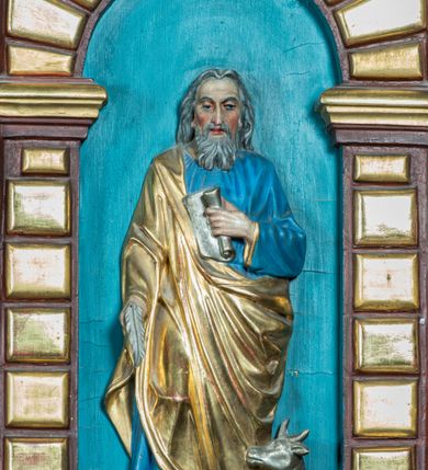 Zdjęcie nr 7: Ambona drewniana, przyścienna, dostępna jednobiegowymi schodkami od strony prezbiterium. Kosz na planie ośmioboku, na cokole dekorowanym złoconym ornamentem małżowinowym; artykułowany pilastrami wspierającymi fryz wypełniony złoconym ornamentem małżowinowym. Na trzonach pilastrów złocony ornament kwiatowy podwieszony na wstędze regencyjnej. W polach płyciny ujęte boniowanymi arkadkami mieszczącymi płaskorzeźbione, całopostaciowe przedstawienia ewangelistów na niebieskim tle. Całość zwieńczona profilowanym gzymsem. Zaplecek z półkolistą niszą mieszczącą płaskorzeźbione przedstawienie Chrystusa Dobrego Pasterza, ujętą pilastrami dźwigającymi niepełne belkowanie. Na trzonach podwieszone złocone zwisy kwiatowe przewiązane karbowaną wstęgą. Baldachim ośmioboczny z silnie występującym, profilowanym gzymsem. W podniebiu płaskorzeźbione przedstawienie gołębicy Ducha Świętego. W zwieńczeniu, na ośmiobocznym postumencie wolnostojąca, pełnoplastyczna rzeźba anioła grającego na trąbie. Figury ewangelistów ukazane frontalnie, w postawie stojącej, w dłoniach z których jedna jest złożona na piersi, trzymają pióra oraz zwoje lub księgi. Mają twarze podłużne, okolone brodami i średniej długości włosami. W pierwszej arkadzie od lewej strony ukazany jest św. Mateusz z małą postacią człowieka u nóg. Święty ubrany jest w brązową suknię oraz złoty płaszcz; ma siwe włosy. W kolejnej arkadzie św. Marek, a za nim lew. Święty ubrany jest w fioletową suknię i złocony płaszcz. W następnej arkadzie św. Łukasz, obok którego wyłania się wół. Ubrany jest w niebieską suknię i złocony płaszcz; ma siwe włosy i brodę. W ostatniej arkadzie ukazano św. Jana z orłem u stóp, ubranego w zieloną suknię i złocony płaszcz, bez zarostu, z długimi i jasnymi włosami. Chrystus ukazany frontalnie z barankiem założonym na barku, przytrzymujący go lewą ręką, z kijem pasterskim w prawej dłoni i drugim barankiem u stóp. Twarz podłużna o głęboko osadzonych, dużych oczach, okolona krótką brodą i długimi włosami. U szczytu anioł grający na trąbie. Ubrany jest w jasnofioletową suknię oraz krótką złoconą tunikę. Struktura malowana na ciemny brąz, partie ornamentu złocone.