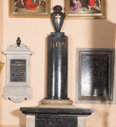 Zdjęcie nr 1: Nagrobek utworzony z wysokiego cokołu z tablicą inskrypcyjną oraz kolumny stojącej na bazie i zwieńczonej urną zdobioną złoconym krzyżem. Na kolumnie inskrypcja: &quot;D(EO) O(PTIMO) M(AXIMO)&quot;. Na tablicy na cokole inskrypcja &quot;Tu spoczywają zwłoki ś(więtej) p(amięci) / JANA KANTEGO KIRCHMAJERA / Sędziego Pokoju okręgu Mogilskiego. Dziedzica wsi Krzesławic / który przeżywszy lat 39, a w małżeństwie lat 7, w czasie okropnej choroby Cholera Morbus / zwanej z troskliwością Oycowską ratując swoich poddanych, niosąc im własną ręką / pomoc, z narażeniem życia, sam nakoniec dnia 23. lipca r(oku) 1831. na tęż chorobę / przeniósł się do wieczności / Pozostała żona Aniela z Dorawow KIRCHMAJEROWA, / opłakując nieodzałowaną stratę najlepszego męża, na wieczną pamiątkę miłości, / pomnik ten poświęca&quot;. 