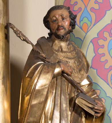 Zdjęcie nr 1: Rzeźba ścięta z tyłu, drążona, ustawiona na prostopadłościennej niskiej podstawie. Postać ukazana w kontrapoście, frontalnie, z głową skierowaną w prawo. Prawą ręką przytrzymuje na piersi kwiat lilii, w lewej zamkniętą księgę. Jego twarz jest ascetyczna, nos krótki z wgłębieniem nad nim, o głęboko rzeźbionych rysach, wyraźnie zaznaczonych brwiach wysoko uniesionych, widocznych zmarszczkach wzdłuż policzków, wąskich i szeroko otwartych oczach, ustach pełnych, nieznacznie rozchylonych. Twarz okolona krótką, szpiczastą, kręconą brodą. Włosy krótkie, rzeźbione w pojedyncze pukle opadające na tył głowy. Święty jest ubrany w tunikę, togę profesorską z szerokimi rękawami, rozchyloną na przodzie, ściśle przylegającą do ciała, swobodnie drapowaną w pojedyncze fałdy, odpowiadające układowi ciała, z gronostajowym kołnierzem na piersi. 
Polichromia naturalistyczna w odsłoniętych partiach ciała; szaty i atrybuty złocone.