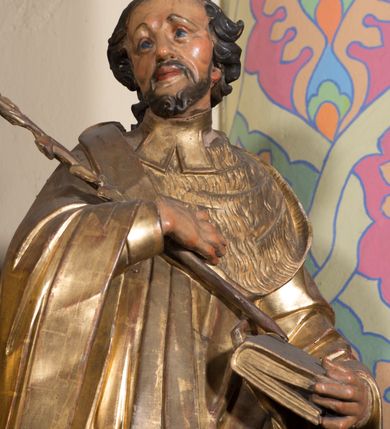 Zdjęcie nr 3: Rzeźba ścięta z tyłu, drążona, ustawiona na prostopadłościennej niskiej podstawie. Postać ukazana w kontrapoście, frontalnie, z głową skierowaną w prawo. Prawą ręką przytrzymuje na piersi kwiat lilii, w lewej zamkniętą księgę. Jego twarz jest ascetyczna, nos krótki z wgłębieniem nad nim, o głęboko rzeźbionych rysach, wyraźnie zaznaczonych brwiach wysoko uniesionych, widocznych zmarszczkach wzdłuż policzków, wąskich i szeroko otwartych oczach, ustach pełnych, nieznacznie rozchylonych. Twarz okolona krótką, szpiczastą, kręconą brodą. Włosy krótkie, rzeźbione w pojedyncze pukle opadające na tył głowy. Święty jest ubrany w tunikę, togę profesorską z szerokimi rękawami, rozchyloną na przodzie, ściśle przylegającą do ciała, swobodnie drapowaną w pojedyncze fałdy, odpowiadające układowi ciała, z gronostajowym kołnierzem na piersi. 
Polichromia naturalistyczna w odsłoniętych partiach ciała; szaty i atrybuty złocone.