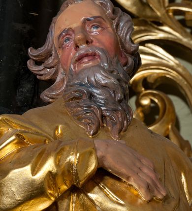 Zdjęcie nr 4: Rzeźba ścięta z tyłu, drążona, ustawiona na niskiej podstawie. Figura zwrócona w trzech czwartych w lewo, z głową ukazaną frontalnie, lekko przechyloną na prawe ramię. Święty stoi w kontrapoście, delikatnie przechylając się do tyłu. Jego prawa ręka spoczywa na piersi, a w lewej odchylonej od ciała trzyma wiosło. Jego twarz jest szczupła, o wyraźnie podkreślonych i wygiętych łukach brwiowych, oczy głęboko osadzone, spoglądające ku górze, nos krótki, szeroki, usta pełne i delikatnie rozchylone. Twarz okala długa broda, opadająca faliście na pierś. Włosy kręcone, formowane w osobne pukle, ekspresyjnie rozwiane. Święty jest ubrany w długą szatę o wąskich rękawach, przepasaną w talii, ściśle przylegającą do ciała w partii torsu, układającą się w ostre fałdy u dołu. Polichromia naturalistyczna w odsłoniętych partiach ciała, szaty i atrybut złocony.