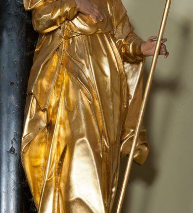 Zdjęcie nr 3: Rzeźba ścięta z tyłu, drążona, ustawiona na niskiej podstawie. Figura zwrócona w trzech czwartych w lewo, z głową ukazaną frontalnie, lekko przechyloną na prawe ramię. Święty stoi w kontrapoście, delikatnie przechylając się do tyłu. Jego prawa ręka spoczywa na piersi, a w lewej odchylonej od ciała trzyma wiosło. Jego twarz jest szczupła, o wyraźnie podkreślonych i wygiętych łukach brwiowych, oczy głęboko osadzone, spoglądające ku górze, nos krótki, szeroki, usta pełne i delikatnie rozchylone. Twarz okala długa broda, opadająca faliście na pierś. Włosy kręcone, formowane w osobne pukle, ekspresyjnie rozwiane. Święty jest ubrany w długą szatę o wąskich rękawach, przepasaną w talii, ściśle przylegającą do ciała w partii torsu, układającą się w ostre fałdy u dołu. Polichromia naturalistyczna w odsłoniętych partiach ciała, szaty i atrybut złocony.