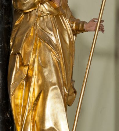 Zdjęcie nr 2: Rzeźba ścięta z tyłu, drążona, ustawiona na niskiej podstawie. Figura zwrócona w trzech czwartych w lewo, z głową ukazaną frontalnie, lekko przechyloną na prawe ramię. Święty stoi w kontrapoście, delikatnie przechylając się do tyłu. Jego prawa ręka spoczywa na piersi, a w lewej odchylonej od ciała trzyma wiosło. Jego twarz jest szczupła, o wyraźnie podkreślonych i wygiętych łukach brwiowych, oczy głęboko osadzone, spoglądające ku górze, nos krótki, szeroki, usta pełne i delikatnie rozchylone. Twarz okala długa broda, opadająca faliście na pierś. Włosy kręcone, formowane w osobne pukle, ekspresyjnie rozwiane. Święty jest ubrany w długą szatę o wąskich rękawach, przepasaną w talii, ściśle przylegającą do ciała w partii torsu, układającą się w ostre fałdy u dołu. Polichromia naturalistyczna w odsłoniętych partiach ciała, szaty i atrybut złocony.