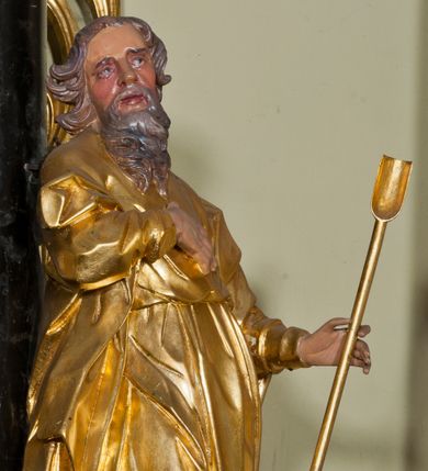 Zdjęcie nr 1: Rzeźba ścięta z tyłu, drążona, ustawiona na niskiej podstawie. Figura zwrócona w trzech czwartych w lewo, z głową ukazaną frontalnie, lekko przechyloną na prawe ramię. Święty stoi w kontrapoście, delikatnie przechylając się do tyłu. Jego prawa ręka spoczywa na piersi, a w lewej odchylonej od ciała trzyma wiosło. Jego twarz jest szczupła, o wyraźnie podkreślonych i wygiętych łukach brwiowych, oczy głęboko osadzone, spoglądające ku górze, nos krótki, szeroki, usta pełne i delikatnie rozchylone. Twarz okala długa broda, opadająca faliście na pierś. Włosy kręcone, formowane w osobne pukle, ekspresyjnie rozwiane. Święty jest ubrany w długą szatę o wąskich rękawach, przepasaną w talii, ściśle przylegającą do ciała w partii torsu, układającą się w ostre fałdy u dołu. Polichromia naturalistyczna w odsłoniętych partiach ciała, szaty i atrybut złocony.