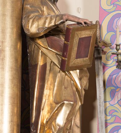 Zdjęcie nr 5: Rzeźba ścięta z tyłu, drążona, ustawiona na cokole w formie kostki. Figura ustawiona w kontrapoście, zwrócona frontalnie, o esowato wygiętej sylwetce. W lewej, odsuniętej od boku ręce trzyma miecz, zwrócony ostrzem w dół, prawą podtrzymuje na udzie zamkniętą księgę. Twarz ma pociągłą, szczupłą, oczy w głębokich oczodołach z silnie zaznaczonymi i podniesionymi łukami brwiowymi, nos mały, usta pełne. Jego twarz jest okolona długą brodą opadającą lokami na pierś z rozdwojonymi końcówkami. Włosy kręcone, głęboko rzeźbione, sięgające szyi. Święty jest ubrany w tunikę o wąskich, drapowanych rękawach, ściśle przylegającą do ciała, przepasaną w talii szarfą oraz obficie drapowany i łamany płaszcz przewiązany przez lewe ramię i opadający na prawą nogę. Polichromia naturalistyczna w odsłoniętych partiach ciała, szaty złocone, atrybuty złocone i srebrzone.
