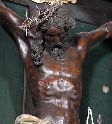 Zdjęcie nr 3: Chrystus ukazany w typie christo morte, w silnym zwisie, z głową opadającą na prawe ramię, nogami delikatnie ugiętymi w kolanach i skrzyżowanymi stopami przebitymi jednym gwoździem. Twarz pociągła, szczupła o wyraźnie zaznaczonych kościach policzkowych i długim nosie, z zamkniętymi oczami. Twarz okolona krótką, falowaną brodą. Włosy falowane, długie opadające na prawie ramię. Ciało szczupłe, o wyraźnie zarysowanej muskulaturze i klatce piersiowej. Perizonium gęsto drapowane w drobne fałdki, ściśle opinające biodra, przewiązane po prawej stronie, ze zwisem tkaniny sięgającym kolan.  Na górnej belce krzyża titulus w formie kartusza, z dekoracją małżowinową oraz napisem "INRI". Ciało polichromowane na brązowo, szaty złocone.