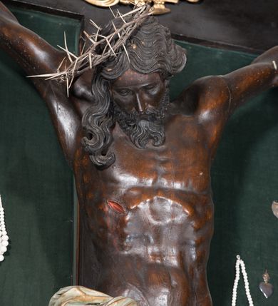 Zdjęcie nr 8: Chrystus ukazany w typie christo morte, w silnym zwisie, z głową opadającą na prawe ramię, nogami delikatnie ugiętymi w kolanach i skrzyżowanymi stopami przebitymi jednym gwoździem. Twarz pociągła, szczupła o wyraźnie zaznaczonych kościach policzkowych i długim nosie, z zamkniętymi oczami. Twarz okolona krótką, falowaną brodą. Włosy falowane, długie opadające na prawie ramię. Ciało szczupłe, o wyraźnie zarysowanej muskulaturze i klatce piersiowej. Perizonium gęsto drapowane w drobne fałdki, ściśle opinające biodra, przewiązane po prawej stronie, ze zwisem tkaniny sięgającym kolan.  Na górnej belce krzyża titulus w formie kartusza, z dekoracją małżowinową oraz napisem "INRI". Ciało polichromowane na brązowo, szaty złocone.