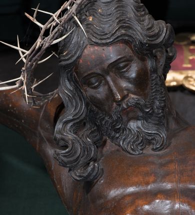 Zdjęcie nr 7: Chrystus ukazany w typie christo morte, w silnym zwisie, z głową opadającą na prawe ramię, nogami delikatnie ugiętymi w kolanach i skrzyżowanymi stopami przebitymi jednym gwoździem. Twarz pociągła, szczupła o wyraźnie zaznaczonych kościach policzkowych i długim nosie, z zamkniętymi oczami. Twarz okolona krótką, falowaną brodą. Włosy falowane, długie opadające na prawie ramię. Ciało szczupłe, o wyraźnie zarysowanej muskulaturze i klatce piersiowej. Perizonium gęsto drapowane w drobne fałdki, ściśle opinające biodra, przewiązane po prawej stronie, ze zwisem tkaniny sięgającym kolan.  Na górnej belce krzyża titulus w formie kartusza, z dekoracją małżowinową oraz napisem "INRI". Ciało polichromowane na brązowo, szaty złocone.