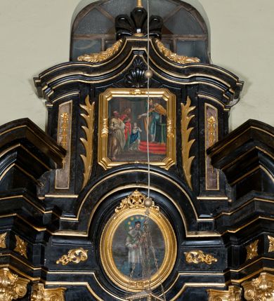 Zdjęcie nr 3: Obraz w formie stojącego prostokąta o ściętych narożach, w drewnianej, złoconej, profilowanej ramie z ornamentem roślinnym. W centrum obrazu postać Marii przedstawionej jako dziewczynka, wstępującej po stopniach na ołtarz. W prawej części obrazu pochylający się ku Marii kapłan. W lewej części kompozycji postacie Anny i Joachima. Maria zwrócona w trzech czwartych w lewo z dłońmi skrzyżowanymi na piersi, jest ubrana w białą suknię i granatowy płaszcz przewiązany przez lewe ramię. Stojący na kilkustopniowym podwyższeniu nakrytym czerwonym dywanem arcykapłan jest ubrany w niebieską tunikę, na którą zarzucony jest żółty płaszcz, a głowę nakrywa mitra. Przed nim znajduje się stolik nakryty zielonym suknem, na nim opiera przytrzymywaną lewą dłonią księgę. Joachim jest ubrany w jasną suknię i jasny płaszcz przytrzymywany w prawej dłoni; na ręce zawieszony ma koszyk z gołębiami. Anna jest ubrana w zieloną suknię, czerwony płaszcz i żółtą chustę na głowie. Ich twarze modelowane są sumarycznie, szkicowo. W tle fragment architektury z rozpostartą zieloną kotarą.  