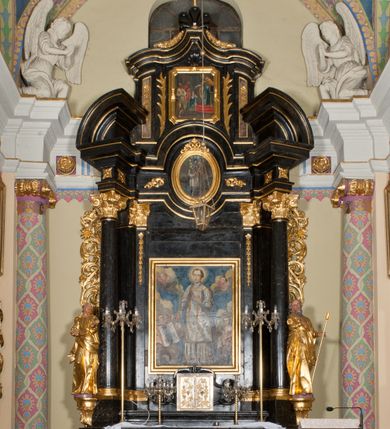 Zdjęcie nr 1: Ołtarz jednoosiowy, jednokondygnacyjny ze zwieńczeniem. Mensa marmurowa, antepedium z płyciną w kształcie leżącego prostokąta o ściętych ćwierćkoliście narożach oraz drewnianym i płaskorzeźbionym przedstawieniem Baranka Eucharystycznego leżącego na księdze, na obłoku, w glorii. Nastawa ujęta parą stojących na ukośnie dostawionych postumentach kolumn kompozytowych na tle zwielokrotnionych pilastrów, dźwigających pełne belkowanie z wydatnym gzymsem, wyłamane na osi podpór oraz przerwany półkolisty przyczółek. Belkowanie rozerwane owalnym polem z obrazem ukazującym św. Jana Nepomucena. Po zewnętrznej stronie podpór figury św. Anny i św. Joachima na wydatnych wspornikach. W polu środkowym profilowana rama w formie stojącego prostokąta z obrazem św. Wawrzyńca. Zwieńczenie w formie stojącego prostokąta, ujęte zdwojonymi pilastrami; zamknięte gzymsem przyjmującym kształt łuku w ośli grzbiet zakończonego stylizowaną palmetą. W polu profilowana rama w formie stojącego prostokąta o ściętych narożach z obrazem „Ofiarowanie Marii do świątyni”. Trzony pilastrów dekorowane kampanulami. Imposty dekorowane z trzech stron rozetami, fryz nad polem środkowym retabulum akantem. Kondygnacja ujęta uszami utworzonymi z suchego akantu z motywem słonecznika. Trzony pilastrów zwieńczenia dekorowane płycinami z kampanulami. Pole obrazowe flankowane liśćmi palmowymi, zwieńczone kamienną muszlą. Na gzymsie zwieńczenia umieszczono festony. Ornamentyka, profilowania i kapitele kolumn są złocone.