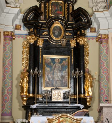 Zdjęcie nr 2: Ołtarz jednoosiowy, jednokondygnacyjny ze zwieńczeniem. Mensa marmurowa, antepedium z płyciną w kształcie leżącego prostokąta o ściętych ćwierćkoliście narożach oraz drewnianym i płaskorzeźbionym przedstawieniem Baranka Eucharystycznego leżącego na księdze, na obłoku, w glorii. Nastawa ujęta parą stojących na ukośnie dostawionych postumentach kolumn kompozytowych na tle zwielokrotnionych pilastrów, dźwigających pełne belkowanie z wydatnym gzymsem, wyłamane na osi podpór oraz przerwany półkolisty przyczółek. Belkowanie rozerwane owalnym polem z obrazem ukazującym św. Jana Nepomucena. Po zewnętrznej stronie podpór figury św. Anny i św. Joachima na wydatnych wspornikach. W polu środkowym profilowana rama w formie stojącego prostokąta z obrazem św. Wawrzyńca. Zwieńczenie w formie stojącego prostokąta, ujęte zdwojonymi pilastrami; zamknięte gzymsem przyjmującym kształt łuku w ośli grzbiet zakończonego stylizowaną palmetą. W polu profilowana rama w formie stojącego prostokąta o ściętych narożach z obrazem „Ofiarowanie Marii do świątyni”. Trzony pilastrów dekorowane kampanulami. Imposty dekorowane z trzech stron rozetami, fryz nad polem środkowym retabulum akantem. Kondygnacja ujęta uszami utworzonymi z suchego akantu z motywem słonecznika. Trzony pilastrów zwieńczenia dekorowane płycinami z kampanulami. Pole obrazowe flankowane liśćmi palmowymi, zwieńczone kamienną muszlą. Na gzymsie zwieńczenia umieszczono festony. Ornamentyka, profilowania i kapitele kolumn są złocone.