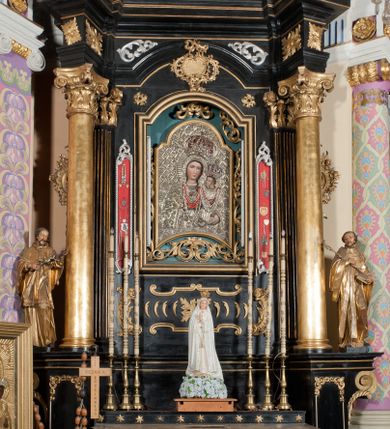 Zdjęcie nr 1: Ołtarz architektoniczny, jednoosiowy, jednokondygnacyjny ze zwieńczeniem. Ołtarz drewniany prostopadłościenny, mensa drewniana z portatylem z marmuru dębnickiego. Antepedium dekorowane płyciną w formie leżącego prostokąta o wklęsłych narożach z monogramem maryjnym w polu. Na ściankach bocznych ołtarza płyciny w formie kwadratu o wklęsłych narożach. Retabulum jest ujęte parą ustawionych pod kątem na cokołach kolumn o kompozytowych kapitelach stojących na tle zwielokrotnionych pilastrów o kanelowanych trzonach, dźwigających pełne belkowanie z wydatnym gzymsem, wyłamane na osi podpór oraz przerwany, półkolisty przyczółek z figurami siedzących puttów; architraw nad polem środkowym przybiera kształt łuku odcinkowego. Po zewnętrznej stronie kolumn figury św. Jana Nepomucena i św. Jana Kantego na wydatnych konsolach. W polu środkowym nisza ujęta profilowaną ramą w formie stojącego prostokąta zamkniętego łukiem odcinkowym nadwieszonym z obrazem Matki Boskiej z Dzieciątkiem. Zwieńczenie w formie stojącego prostokąta ujęte zwielokrotnionymi pilastrami podtrzymującymi profilowany gzyms w kształcie łuku oślego. W polu owalny obraz "Św. Andrzej". Cokoły dekorowane płycinami utworzonymi z ornamentu roślinnego, konsole zdobione muszlą o kształcie falbany. Nad polem środkowym rocaille'owy kartusz, flankowany akantem. U spodu obrazu dekoracja roślinno-geometryczna z rozetą ujętą rocaiile'm. Obraz flankowany gablotami z wotami w ramie utworzonej z akantu i sznura. Fryz impostów zdobiony rozetami; nad polem środkowym akantem. Kondygnacja ujęta ażurowymi uszami utworzonymi z rocaille'ów i kwiatów róż. Trzony pilastrów zwieńczenia dekorowane rocaille'em i roślinnymi festonami. Pole obrazowe otoczone fragmentami rocaille'u, zwieńczone muszlą. Nad zwieńczeniem mitra książęca. Struktura polichromowana w kolorze czarnym; kolumny, ornamentyka i profile złocone.