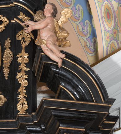 Zdjęcie nr 4: Ołtarz architektoniczny, jednoosiowy, jednokondygnacyjny ze zwieńczeniem. Ołtarz drewniany prostopadłościenny, mensa drewniana z portatylem z marmuru dębnickiego. W ołtarzu nisza z Grobem Pańskim, zakryta antepedium dekorowanym ramą w formie leżącego prostokąta o wklęsłych narożach z monogramem IHS w polu. Na ściankach bocznych ołtarza płyciny w formie kwadratu o wklęsłych narożach. Retabulum jest ujęte parą kompozytowych kolumn ustawionych na ukośnych cokołach stojących, na tle zwielokrotnionych pilastrów o kanelowanych trzonach, dźwigających pełne belkowanie z wydatnym gzymsem wyłamane na osi podpór oraz przerwany półkolisty przyczółek z figurami siedzących puttów; architraw nad polem środkowym przybiera kształt łuku odcinkowego. Po zewnętrznej stronie kolumn figury św. Piotra i św. Pawła stojące na wydatnych konsolach. W polu środkowym nisza ujęta profilowaną ramą w formie stojącego prostokąta zamkniętego łukiem odcinkowym nadwieszonym z figurą Chrystusa Ukrzyżowanego. Zwieńczenie w formie stojącego prostokąta ujęte zwielokrotnionymi pilastrami podtrzymującymi profilowany gzyms przyjmujący kształt łuku oślego. W polu owalne pole z obrazem „Zesłanie Ducha Świętego”. Cokoły dekorowane płycinami utworzonymi z ornamentu roślinnego, zaś konsole zdobione muszlą o kształcie falbany. Nad polem środkowym rocaille'owy kartusz z napisem: „IXEUS”, flankowany akantem. U spodu obrazu prostokątna płycina. Fryz zdobiony rozetami. Kondygnacja ujęta ażurowymi uszami utworzonymi z suchego akantu, wstęgi, rocaille'u i rozet. Trzony pilastrów zwieńczenia dekorowane rocaille'em i roślinnymi festonami. Pole obrazowe otoczone fragmentami rocaille'u, zwieńczone muszlą. Ponad zwieńczeniem krzyż lub wazon nakryty sukienką na puszkę. Struktura polichromowana w kolorze czarnym; kolumny, ornamentyka i profile złocone.