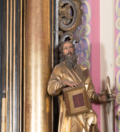 Zdjęcie nr 21: Ołtarz architektoniczny, jednoosiowy, jednokondygnacyjny ze zwieńczeniem. Ołtarz drewniany prostopadłościenny, mensa drewniana z portatylem z marmuru dębnickiego. W ołtarzu nisza z Grobem Pańskim, zakryta antepedium dekorowanym ramą w formie leżącego prostokąta o wklęsłych narożach z monogramem IHS w polu. Na ściankach bocznych ołtarza płyciny w formie kwadratu o wklęsłych narożach. Retabulum jest ujęte parą kompozytowych kolumn ustawionych na ukośnych cokołach stojących, na tle zwielokrotnionych pilastrów o kanelowanych trzonach, dźwigających pełne belkowanie z wydatnym gzymsem wyłamane na osi podpór oraz przerwany półkolisty przyczółek z figurami siedzących puttów; architraw nad polem środkowym przybiera kształt łuku odcinkowego. Po zewnętrznej stronie kolumn figury św. Piotra i św. Pawła stojące na wydatnych konsolach. W polu środkowym nisza ujęta profilowaną ramą w formie stojącego prostokąta zamkniętego łukiem odcinkowym nadwieszonym z figurą Chrystusa Ukrzyżowanego. Zwieńczenie w formie stojącego prostokąta ujęte zwielokrotnionymi pilastrami podtrzymującymi profilowany gzyms przyjmujący kształt łuku oślego. W polu owalne pole z obrazem „Zesłanie Ducha Świętego”. Cokoły dekorowane płycinami utworzonymi z ornamentu roślinnego, zaś konsole zdobione muszlą o kształcie falbany. Nad polem środkowym rocaille'owy kartusz z napisem: „IXEUS”, flankowany akantem. U spodu obrazu prostokątna płycina. Fryz zdobiony rozetami. Kondygnacja ujęta ażurowymi uszami utworzonymi z suchego akantu, wstęgi, rocaille'u i rozet. Trzony pilastrów zwieńczenia dekorowane rocaille'em i roślinnymi festonami. Pole obrazowe otoczone fragmentami rocaille'u, zwieńczone muszlą. Ponad zwieńczeniem krzyż lub wazon nakryty sukienką na puszkę. Struktura polichromowana w kolorze czarnym; kolumny, ornamentyka i profile złocone.