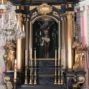 Zdjęcie nr 1: Ołtarz architektoniczny, jednoosiowy, jednokondygnacyjny ze zwieńczeniem. Ołtarz drewniany prostopadłościenny, mensa drewniana z portatylem z marmuru dębnickiego. W ołtarzu nisza z Grobem Pańskim, zakryta antepedium dekorowanym ramą w formie leżącego prostokąta o wklęsłych narożach z monogramem IHS w polu. Na ściankach bocznych ołtarza płyciny w formie kwadratu o wklęsłych narożach. Retabulum jest ujęte parą kompozytowych kolumn ustawionych na ukośnych cokołach stojących, na tle zwielokrotnionych pilastrów o kanelowanych trzonach, dźwigających pełne belkowanie z wydatnym gzymsem wyłamane na osi podpór oraz przerwany półkolisty przyczółek z figurami siedzących puttów; architraw nad polem środkowym przybiera kształt łuku odcinkowego. Po zewnętrznej stronie kolumn figury św. Piotra i św. Pawła stojące na wydatnych konsolach. W polu środkowym nisza ujęta profilowaną ramą w formie stojącego prostokąta zamkniętego łukiem odcinkowym nadwieszonym z figurą Chrystusa Ukrzyżowanego. Zwieńczenie w formie stojącego prostokąta ujęte zwielokrotnionymi pilastrami podtrzymującymi profilowany gzyms przyjmujący kształt łuku oślego. W polu owalne pole z obrazem „Zesłanie Ducha Świętego”. Cokoły dekorowane płycinami utworzonymi z ornamentu roślinnego, zaś konsole zdobione muszlą o kształcie falbany. Nad polem środkowym rocaille'owy kartusz z napisem: „IXEUS”, flankowany akantem. U spodu obrazu prostokątna płycina. Fryz zdobiony rozetami. Kondygnacja ujęta ażurowymi uszami utworzonymi z suchego akantu, wstęgi, rocaille'u i rozet. Trzony pilastrów zwieńczenia dekorowane rocaille'em i roślinnymi festonami. Pole obrazowe otoczone fragmentami rocaille'u, zwieńczone muszlą. Ponad zwieńczeniem krzyż lub wazon nakryty sukienką na puszkę. Struktura polichromowana w kolorze czarnym; kolumny, ornamentyka i profile złocone.