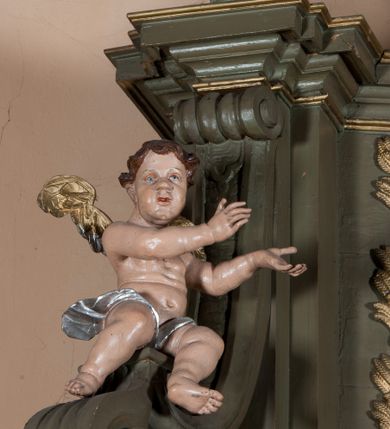 Zdjęcie nr 11: Nastawa architektoniczna, jednokondygnacyjna, jednoosiowa ze zwieńczeniem. Ołtarz sarkofagowy, wybrzuszony, z drewnianą mensą i drewnianym portatylem integralnie zespolony z cokołem retabulum. Nastawa wsparta na ukośnie ustawionych postumentach z filarami i stojącymi przed nimi oraz z boku wolnostojącymi kolumnami z głowicami akantowymi, podtrzymującymi wspólnie, wznoszące się nad nimi belkowanie. Zwieńczenie ujęte ukośnie posadowionymi spływami wolutowymi podtrzymującymi gzyms wyłamujący się pośrodku łukowato. W środku nastawy głęboka wnęka w profilowanym obramieniu z motywem skręconego sznura, prostokątna o ściętych górą narożach, zamknięta łukiem półkolistym nadwieszonym. W niej obraz przedstawiający św. Józefa z Dzieciątkiem, w ramie powielającej wykrój wnęki, z drobnymi rocaille'ami na bokach. W zwieńczeniu wnęka prostokątna w profilowanym obramieniu, z motywem skręconego sznura, ujęta po bokach kłosami zbóż, a zwieńczona motywem akantu. W niej obraz prostokątny obraz z wyobrażeniem św. Stanisława Kostki. Na spływach wolutowych uskrzydlone nagie aniołki z przepaską na biodrach. Nad wnęką w środkowej części ołtarza wypukły kartusz ujęty rocaile'm, drobne rocaille nad wnęką i na filarach, w partii cokołu utworzona z motywu rocaille'owego konsola.  Kolorystyka  struktury w odcieniu  zieleni wpadającej w szarość, partie detalu architektonicznego i ornamentyka  złocone.