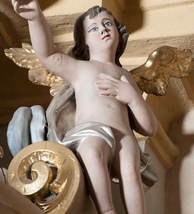 Zdjęcie nr 7: Ambona nadwieszona z dostępem w postaci jednobiegowych schodów usytuowanych z prawej strony kosza. Kosz na rzucie półkolistym, z podwieszoną szyszką u spodu. Ścianki kosza flankowane dwoma spływami wolutowymi. Cokół kosza zaakcentowany szeregiem form przypominających obłoki. Ścianki kosza podzielone na sześć  pionowych, prostokątnych, o wciętych półkoliście krótszych bokach, wypełnionych dekoracją z motywów rocaille. Gzyms profilowany, przełamany na osi spływów. Na wolutach spływów oraz pośrodku kosza osadzone trzy figury aniołków. Zaplecek rozszerzający się ku dołowi, flankowany parą spływów; w jego polu obraz w kształcie pionowego prostokąta zamkniętego łukiem wklęsło-wypukłym z przedstawieniem św. Jana Nepomucena. Zaplecek ujęty z boków i zwieńczony spiętą kotarą z frędzlami. Baldachim na planie analogicznym jak kosz, o wysokim, profilowanym dolnym brzegu, obwiedziony od dołu lambrekinem z frędzlami. W polu podniebienia baldachimu gołębica Ducha Świętego na tle promienistej glorii, z przodu na brzegu baldachimu kartusz z motywu rocaille. Podniebienie baldachimu w kolorze niebieskim, na polu gołębica Ducha Świętego na tle promienistej glorii, z przodu rocaille'owy kartusz. Szczyt baldachimu w formie wysokiego postumentu, na którym ustawiona rzeźba Michała Archanioła zwyciężającego szatana. Po bokach postumentu dwa rzeźbione aniołki. Święty Michał Archanioł ukazany w pozycji stojącej o esowato wygiętej sylwetce, z prawą ręką uniesioną wysoko ku górze, w której trzyma płomienisty miecz, w lewej owalna tarcza z monogramem Chrystusa i trzema gwoździami, lewą stopą depcze leżącego szatana. Ubrany w strój legionisty rzymskiego, skrzydła złocone, szeroko rozłożone. Szatan ukazany w monstrualnej postaci, w pozycji leżącej na brzuchu, z lewą nogą uniesioną wysoko ku górze. Postać polichromowana na czarno, detale (oczy, usta, rogi, paznokcie) na czerwono. Aniołki ukazane w poruszonych pozach, przepasane srebrną chustką, z szeroko rozłożonymi złoconymi skrzydłami. Balustrada schodów zamknięta od dołu cokołem i od góry profilowanym gzymsem, zdobiona w polu romboidalną płyciną, zakończona słupkiem z wazonem płomienistym na szczycie. Struktura ambony polichromowana na kolor jasno i ciemnobeżowy, detale i płyciny na kolor niebieski, ornamentyka złocona.
