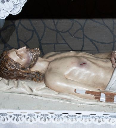Zdjęcie nr 1: Rzeźba przedstawia Chrystusa w grobie. Chrystus ukazany w pozycji leżącej na łożu pośmiertnym z głową lekko przechyloną w prawo, prawa ręka ułożona wzdłuż ciała, lewa spoczywa na tułowiu, nogi ułożone równolegle. Twarz owalna, szczupła, oczy zamknięte, długi i wąski nos, usta lekko rozchylone, okolona średniej długości brodą; włosy sięgające ramion, z przedziałkiem pośrodku, falowane. Chrystus okryty od pasa do kostek  białą szatą ze złotą lamówką na brzegu. Na ciele widoczne rany po gwoździach i włóczni. Łoże wyścielone poduszką. Polichromia w odsłoniętych partiach ciała naturalistyczna.
