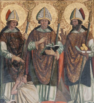 Zdjęcie nr 1: Obraz w kształcie stojącego prostokąta przedstawiający trzech świętych biskupów: Stanisława, Walentego i Mikołaja ukazanych na złotym tle z grawerowanym ornamentem roślinnym. Święci ukazani w całej postaci, w pozycji stojącej. Pośrodku kompozycji św. Walenty przedstawiony frontalnie z prawą ręką uniesioną na wysokości piersi, złożoną w geście błogosławieństwa; lewą ułożoną niżej, przytrzymuje pastorał, a w dłoni trzyma otwartą księgę. Twarz świętego o owalnym kształcie okolona sięgającymi uszu brązowymi włosami, oczy niewielkie i brązowe, brwi wygięte w półkolisty łuk, nos długi i prosty, usta niewielkie z wydatną dolną wargą. Święty Walenty ubrany jest w białą albę, zieloną dalmatykę, biały humerał, złoty ornat z czerwoną podszewką, który ozdobiony jest dekoracją roślinną, ma również założone rękawice oraz infułę. U stóp św. Walentego ukazany jest leżący epileptyk o sylwetce wygiętej w łuk, ręce wysoko uniesione o otwartych dłoniach, głowa odchylona do tyłu. Twarz wykrzywiona w okrzyku, okolona przez opadające, brązowe włosy. Mężczyzna ubrany jest w jasnoczerwoną suknię sięgającą kolan, przewiązaną w pasie czarnym sznurkiem.

Po lewej stronie obrazu ukazany jest św. Stanisław, zwrócony delikatnie w lewą stronę, w lewej ręce trzyma pastorał, a prawą błogosławi klęczącego u jego stóp Piotrawina. Głowa świętego lekko pochylona w dół, twarz okolona spiralnie kręconymi włosami, brwi mocno ściągnięte, oczy przymknięte, nos długi o prostym profilu, usta niewielkie, cera śniada. Święty Stanisław ubrany jest w białą albę, zieloną dalmatykę, biały humerał, złoty ornat, który ozdobiony jest dekoracją roślinną, ma również założone rękawice oraz infułę. Piotrawin ukazany w półpostaci z lewego profilu, z rękoma uniesionymi i złożonymi w geście modlitewnym. Twarz okolona brązowymi, zaczesanymi do tyłu włosami, brwi ściągnięte, nos wydatny, usta szeroko rozwarte.

Po prawej stronie obrazu ukazany jest św. Mikołaj, zwrócony delikatnie w prawo z pastorałem opartym na lewym ramieniu, z lewą dłonią otwartą, podtrzymującą zamkniętą księgę z trzema złotymi kulami; prawą rękę święty unosi w geście błogosławieństwa. Twarz o wyrazistych rysach okolona krótkimi, kręconymi włosami i długą brodą, oczy brązowe o migdałowatym kształcie, brwi lekko ściągnięte, nos wydatny, haczykowaty. Święty Mikołaj ubrany jest w białą albę, zieloną dalmatykę, biały humerał, złoty ornat z czerwoną podszewką, który ozdobiony jest dekoracją roślinną, ma również założone rękawice oraz infułę. Wokół głów świętych są złote nimby, grawerowane w zaprawie. Obraz ujęty jest drewnianą, pozłacaną ramą dekorowaną ornamentem rokokowym.