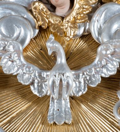 Zdjęcie nr 4: Ołtarz jednoosiowy, jednokondygnacyjny ze zwieńczeniem. Mensa sarkofagowa. Nastawa osadzona na cokole,  flankowana dwoma spływami wolutowymi, obficie dekorowanymi rocaille&#039;ami. W polu głównym, w płytkiej niszy w kształcie stojącego prostokąta zamkniętego łukiem wklęsło-wypukłym z uskokami obraz Matki Boskiej Niepokalanie Poczętej. W dolnej części kondygnacji prostokątne pole utworzone z rocaille&#039;i. Zwieńczenie o wielkości kondygnacji w formie promienistej glorii, z gołębicą Ducha Świętego w polu, wokół której uskrzydlone główki aniołków na tle obłoków oraz rocaille&#039;e spięte u góry koroną w typie otwartym. Struktura polichromowana na kolor jasno i ciemnobeżowy, detale, ornamentyka i profilowania złocone. Taki sam ornament zdobi narożniki mensy, ryzality w cokole, ujmuje również pole obrazowe na jego dłuższych bokach oraz w zwieńczeniu pola.