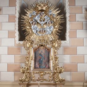 Zdjęcie nr 1: Ołtarz jednoosiowy, jednokondygnacyjny ze zwieńczeniem. Mensa sarkofagowa. Nastawa osadzona na cokole,  flankowana dwoma spływami wolutowymi, obficie dekorowanymi rocaille'ami. W polu głównym, w płytkiej niszy w kształcie stojącego prostokąta zamkniętego łukiem wklęsło-wypukłym z uskokami obraz Matki Boskiej Niepokalanie Poczętej. W dolnej części kondygnacji prostokątne pole utworzone z rocaille'i. Zwieńczenie o wielkości kondygnacji w formie promienistej glorii, z gołębicą Ducha Świętego w polu, wokół której uskrzydlone główki aniołków na tle obłoków oraz rocaille'e spięte u góry koroną w typie otwartym. Struktura polichromowana na kolor jasno i ciemnobeżowy, detale, ornamentyka i profilowania złocone. Taki sam ornament zdobi narożniki mensy, ryzality w cokole, ujmuje również pole obrazowe na jego dłuższych bokach oraz w zwieńczeniu pola.