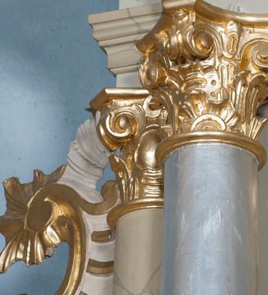 Zdjęcie nr 27: Nastawa ołtarzowa architektoniczna, jednoosiowa, jednokondygnacyjna ze zwieńczeniem, z bramkami i z rocaille'owymi uszami. Tabernakulum w formie zbliżonej do prostopadłościennej skrzynki, na wklęsło-wypukłym rzucie, ustawione na niskim cokole, o wypukłej ściance frontowej. Ujęte jest drewnianą obudową o wklęsłych bokach, flankowane parą ustawionych pod kątem pilastrów, których trzony przyjmują formę wolut. Zwieńczenie tabernakulum w formie niewielkiego szczytu, na którym ustawiona jest pasyjka. Całość ujęta po bokach rocaille'owymi wolutami. Drzwiczki w kształcie stojącego prostokąta, zamknięte łukiem nadwieszonym. W polu, na niebieskim tle malowane przedstawienie kielicha z hostią. Nastawa ustawiona na zdwojonym cokole, o  wklęsłym przebiegu, ujęta dwiema parami kolumn na tle zwielokrotnionych pilastrów. Podpory dźwigają pełne belkowanie, wyłamane pośrodku. Pomiędzy podporami figury: po lewej św. Józefa, a po prawej św. Jana Chrzciciela, nad bramkami: po lewej św. Wojciecha, a po prawej św. Stanisława. Nad tabernakulum rocaille'owy kartusz z łacińską inskrypcją w polu. W polu środkowym nisza w formie stojącego prostokąta, zamkniętego łukiem wklęsło-wypukłym z uskokami z obrazem „Święta Rozmowa”. Zwieńczenie w formie zbliżonej do stojącego prostokąta ujętego po bokach dwoma pilastrami, bogato ozdobione dekoracją rzeźbiarską. W polu przedstawienie Trójcy Świętej, flankowane przez parę aniołów siedzących na wolutowych przyczółkach. Całość zamyka para aniołków ze srebrną wstęgą z napisem „GLORIA IN EXCELSIS DEO”. Bramki z drzwiczkami w formie stojącego prostokąta, flankowane węgarami, zamknięte wolutowym łukiem z zatkniętymi na szczycie rzeźbami świętych. Drzwiczki dekorowane w polu dwiema płycinami. Całość nastawy silnie dekorowana ornamentyką rokokową. Kolumny ustawione na bazach, z kompozytowymi kapitelami, wewnętrzne srebrzone, do jednej trzeciej wysokości zdobione kanelowaniem zamkniętym pierścieniem, kolumny zewnętrzne marmoryzowane. Struktura polichromowana w kolorze beżowym, profilowania marmoryzowane, ornamentyka złocona.