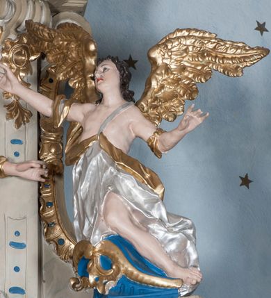 Zdjęcie nr 8: Nastawa ołtarzowa architektoniczna, jednoosiowa, jednokondygnacyjna ze zwieńczeniem, z bramkami i z rocaille'owymi uszami. Tabernakulum w formie zbliżonej do prostopadłościennej skrzynki, na wklęsło-wypukłym rzucie, ustawione na niskim cokole, o wypukłej ściance frontowej. Ujęte jest drewnianą obudową o wklęsłych bokach, flankowane parą ustawionych pod kątem pilastrów, których trzony przyjmują formę wolut. Zwieńczenie tabernakulum w formie niewielkiego szczytu, na którym ustawiona jest pasyjka. Całość ujęta po bokach rocaille'owymi wolutami. Drzwiczki w kształcie stojącego prostokąta, zamknięte łukiem nadwieszonym. W polu, na niebieskim tle malowane przedstawienie kielicha z hostią. Nastawa ustawiona na zdwojonym cokole, o  wklęsłym przebiegu, ujęta dwiema parami kolumn na tle zwielokrotnionych pilastrów. Podpory dźwigają pełne belkowanie, wyłamane pośrodku. Pomiędzy podporami figury: po lewej św. Józefa, a po prawej św. Jana Chrzciciela, nad bramkami: po lewej św. Wojciecha, a po prawej św. Stanisława. Nad tabernakulum rocaille'owy kartusz z łacińską inskrypcją w polu. W polu środkowym nisza w formie stojącego prostokąta, zamkniętego łukiem wklęsło-wypukłym z uskokami z obrazem „Święta Rozmowa”. Zwieńczenie w formie zbliżonej do stojącego prostokąta ujętego po bokach dwoma pilastrami, bogato ozdobione dekoracją rzeźbiarską. W polu przedstawienie Trójcy Świętej, flankowane przez parę aniołów siedzących na wolutowych przyczółkach. Całość zamyka para aniołków ze srebrną wstęgą z napisem „GLORIA IN EXCELSIS DEO”. Bramki z drzwiczkami w formie stojącego prostokąta, flankowane węgarami, zamknięte wolutowym łukiem z zatkniętymi na szczycie rzeźbami świętych. Drzwiczki dekorowane w polu dwiema płycinami. Całość nastawy silnie dekorowana ornamentyką rokokową. Kolumny ustawione na bazach, z kompozytowymi kapitelami, wewnętrzne srebrzone, do jednej trzeciej wysokości zdobione kanelowaniem zamkniętym pierścieniem, kolumny zewnętrzne marmoryzowane. Struktura polichromowana w kolorze beżowym, profilowania marmoryzowane, ornamentyka złocona.