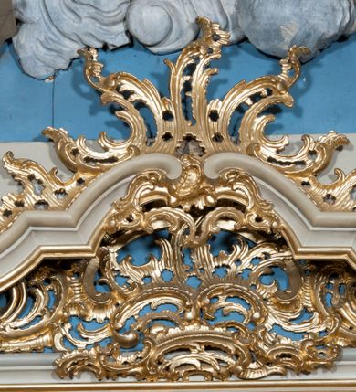 Zdjęcie nr 24: Nastawa ołtarzowa architektoniczna, jednoosiowa, jednokondygnacyjna ze zwieńczeniem, z bramkami i z rocaille'owymi uszami. Tabernakulum w formie zbliżonej do prostopadłościennej skrzynki, na wklęsło-wypukłym rzucie, ustawione na niskim cokole, o wypukłej ściance frontowej. Ujęte jest drewnianą obudową o wklęsłych bokach, flankowane parą ustawionych pod kątem pilastrów, których trzony przyjmują formę wolut. Zwieńczenie tabernakulum w formie niewielkiego szczytu, na którym ustawiona jest pasyjka. Całość ujęta po bokach rocaille'owymi wolutami. Drzwiczki w kształcie stojącego prostokąta, zamknięte łukiem nadwieszonym. W polu, na niebieskim tle malowane przedstawienie kielicha z hostią. Nastawa ustawiona na zdwojonym cokole, o  wklęsłym przebiegu, ujęta dwiema parami kolumn na tle zwielokrotnionych pilastrów. Podpory dźwigają pełne belkowanie, wyłamane pośrodku. Pomiędzy podporami figury: po lewej św. Józefa, a po prawej św. Jana Chrzciciela, nad bramkami: po lewej św. Wojciecha, a po prawej św. Stanisława. Nad tabernakulum rocaille'owy kartusz z łacińską inskrypcją w polu. W polu środkowym nisza w formie stojącego prostokąta, zamkniętego łukiem wklęsło-wypukłym z uskokami z obrazem „Święta Rozmowa”. Zwieńczenie w formie zbliżonej do stojącego prostokąta ujętego po bokach dwoma pilastrami, bogato ozdobione dekoracją rzeźbiarską. W polu przedstawienie Trójcy Świętej, flankowane przez parę aniołów siedzących na wolutowych przyczółkach. Całość zamyka para aniołków ze srebrną wstęgą z napisem „GLORIA IN EXCELSIS DEO”. Bramki z drzwiczkami w formie stojącego prostokąta, flankowane węgarami, zamknięte wolutowym łukiem z zatkniętymi na szczycie rzeźbami świętych. Drzwiczki dekorowane w polu dwiema płycinami. Całość nastawy silnie dekorowana ornamentyką rokokową. Kolumny ustawione na bazach, z kompozytowymi kapitelami, wewnętrzne srebrzone, do jednej trzeciej wysokości zdobione kanelowaniem zamkniętym pierścieniem, kolumny zewnętrzne marmoryzowane. Struktura polichromowana w kolorze beżowym, profilowania marmoryzowane, ornamentyka złocona.