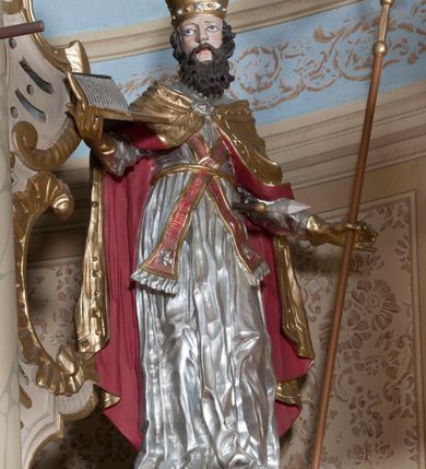 Zdjęcie nr 23: Nastawa ołtarzowa architektoniczna, jednoosiowa, jednokondygnacyjna ze zwieńczeniem, z bramkami i z rocaille'owymi uszami. Tabernakulum w formie zbliżonej do prostopadłościennej skrzynki, na wklęsło-wypukłym rzucie, ustawione na niskim cokole, o wypukłej ściance frontowej. Ujęte jest drewnianą obudową o wklęsłych bokach, flankowane parą ustawionych pod kątem pilastrów, których trzony przyjmują formę wolut. Zwieńczenie tabernakulum w formie niewielkiego szczytu, na którym ustawiona jest pasyjka. Całość ujęta po bokach rocaille'owymi wolutami. Drzwiczki w kształcie stojącego prostokąta, zamknięte łukiem nadwieszonym. W polu, na niebieskim tle malowane przedstawienie kielicha z hostią. Nastawa ustawiona na zdwojonym cokole, o  wklęsłym przebiegu, ujęta dwiema parami kolumn na tle zwielokrotnionych pilastrów. Podpory dźwigają pełne belkowanie, wyłamane pośrodku. Pomiędzy podporami figury: po lewej św. Józefa, a po prawej św. Jana Chrzciciela, nad bramkami: po lewej św. Wojciecha, a po prawej św. Stanisława. Nad tabernakulum rocaille'owy kartusz z łacińską inskrypcją w polu. W polu środkowym nisza w formie stojącego prostokąta, zamkniętego łukiem wklęsło-wypukłym z uskokami z obrazem „Święta Rozmowa”. Zwieńczenie w formie zbliżonej do stojącego prostokąta ujętego po bokach dwoma pilastrami, bogato ozdobione dekoracją rzeźbiarską. W polu przedstawienie Trójcy Świętej, flankowane przez parę aniołów siedzących na wolutowych przyczółkach. Całość zamyka para aniołków ze srebrną wstęgą z napisem „GLORIA IN EXCELSIS DEO”. Bramki z drzwiczkami w formie stojącego prostokąta, flankowane węgarami, zamknięte wolutowym łukiem z zatkniętymi na szczycie rzeźbami świętych. Drzwiczki dekorowane w polu dwiema płycinami. Całość nastawy silnie dekorowana ornamentyką rokokową. Kolumny ustawione na bazach, z kompozytowymi kapitelami, wewnętrzne srebrzone, do jednej trzeciej wysokości zdobione kanelowaniem zamkniętym pierścieniem, kolumny zewnętrzne marmoryzowane. Struktura polichromowana w kolorze beżowym, profilowania marmoryzowane, ornamentyka złocona.