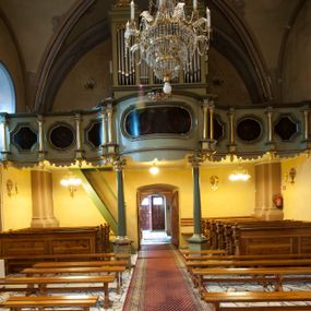 Zdjęcie nr 1: Chór muzyczny architektoniczny, siedmioosiowy. Parapet chóru o falistym, wklęsło-wypukłym przebiegu wsparty na dwóch kolumnach, z bazą i kompozytowymi kapitelami, ustawionych na wysokich postumentach w formie prostopadłościanu. Balustrada pełna podzielona na siedem pól, wydzielonych kolumienkami na cokołach wspierającymi wyłamane belkowanie zamknięte gzymsem. W polach płyciny naprzemiennie w formie owalu i kwadratu o wklęsłych narożach; z malowaną na desce dekoracją roślinną na czarnym tle. Cokoły kolumn z podwieszonymi szyszkami od dołu. Nad polem środkowym dwie uskrzydlone główki anielskie. 
Organy architektoniczne, pięcioosiowe, z wydzielonymi trzema osiami. Osie zewnętrzne z prześwitami na piszczałki w formie stojącego prostokąta, zakończone profilowanym gzymsem. Dwie środkowe osie z prześwitami na piszczałki w formie stojącego prostokąta o wklęsłym górnym zamknięciu, zwieńczone profilowanym gzymsem pośrodku. W wypełnieniach naroży i na gzymsach ażurowe ornamenty roślinne. Struktura polichromowana w kolorze seledynowym z zielonymi profilami, ornamentyka i kolumny złocone.
