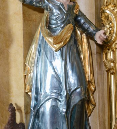 Zdjęcie nr 7: Nastawa ołtarzowa architektoniczna, jednoosiowa, jednokondygnacyjna ze zwieńczeniem. Ołtarz drewniany, prostopadłościenny, mensa drewniana z kamiennym portatylem. Antepedium w kształcie leżącego prostokąta, ujętego profilowaną ramą z aplikowanym monogramem Maryii w polu. Na ołtarzu ustawiony obraz Matki Boskiej Nieustającej Pomocy. Retabulum ustawione na dwustrefowym cokole, ujęte parą kolumn o kapitelach kompozytowych, przewiązanych poniżej połowy rocaille&#039;ową opaską, stojących na tle zwielokrotnionych pilastrów. Podpory dźwigają pełne belkowanie, wyłamane na ich osi, ustawione ukośnie, nad polem środkowym przyjmujące kształt łuku odcinkowego. W polu środkowym głęboka nisza w formie stojącego prostokąta zamkniętego łukiem wklęsło-wypukłym z uskokami, ujęta profilowaną ramą, z figurą Matki Boskiej z Lourdes. Niszę flankują dwie figury: św. Jana i św. Mateusza ustawione na konsolach. Na belkowaniu, na linii podpór cokoły z figurami św. Emeryka i św. Władysława. Zwieńczenie przyjmuje kształt stojącego prostokąta flankowanego spływami wolutowymi, zamkniętego gzymsem przechodzącym w dwie woluty. Całość zakończona promienistą glorią z monogramem Marii otoczonym obłokami, flankowana figurkami aniołków. W polu zwieńczenia rama w formie stojącego prostokąta o wklęsłych bokach i dolnych narożach, zamknięta wolutami, z figurą św. Stefana w polu, ustawioną na wsporniku. Nastawa ujęta po bokach ażurowymi uszami utworzonymi z rocaille&#039;u i prostej karbowanej wstęgi. Całość obficie dekorowana ornamentem rocaille&#039;owym oraz zwisami kwiatowymi. Struktura marmoryzowana w kolorze żółtym, profile marmoryzowane na seledynowo, ornamentyka i profilowania złocone.

