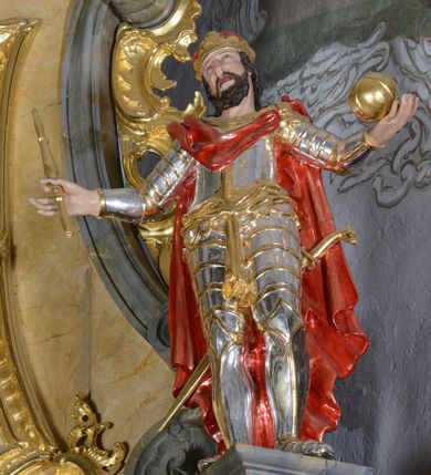 Zdjęcie nr 4: Nastawa ołtarzowa architektoniczna, jednoosiowa, jednokondygnacyjna ze zwieńczeniem. Ołtarz drewniany, prostopadłościenny, mensa drewniana z kamiennym portatylem. Antepedium w kształcie leżącego prostokąta, ujętego profilowaną ramą z aplikowanym monogramem Maryii w polu. Na ołtarzu ustawiony obraz Matki Boskiej Nieustającej Pomocy. Retabulum ustawione na dwustrefowym cokole, ujęte parą kolumn o kapitelach kompozytowych, przewiązanych poniżej połowy rocaille&#039;ową opaską, stojących na tle zwielokrotnionych pilastrów. Podpory dźwigają pełne belkowanie, wyłamane na ich osi, ustawione ukośnie, nad polem środkowym przyjmujące kształt łuku odcinkowego. W polu środkowym głęboka nisza w formie stojącego prostokąta zamkniętego łukiem wklęsło-wypukłym z uskokami, ujęta profilowaną ramą, z figurą Matki Boskiej z Lourdes. Niszę flankują dwie figury: św. Jana i św. Mateusza ustawione na konsolach. Na belkowaniu, na linii podpór cokoły z figurami św. Emeryka i św. Władysława. Zwieńczenie przyjmuje kształt stojącego prostokąta flankowanego spływami wolutowymi, zamkniętego gzymsem przechodzącym w dwie woluty. Całość zakończona promienistą glorią z monogramem Marii otoczonym obłokami, flankowana figurkami aniołków. W polu zwieńczenia rama w formie stojącego prostokąta o wklęsłych bokach i dolnych narożach, zamknięta wolutami, z figurą św. Stefana w polu, ustawioną na wsporniku. Nastawa ujęta po bokach ażurowymi uszami utworzonymi z rocaille&#039;u i prostej karbowanej wstęgi. Całość obficie dekorowana ornamentem rocaille&#039;owym oraz zwisami kwiatowymi. Struktura marmoryzowana w kolorze żółtym, profile marmoryzowane na seledynowo, ornamentyka i profilowania złocone.

