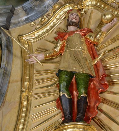 Zdjęcie nr 6: Nastawa ołtarzowa architektoniczna, jednoosiowa, jednokondygnacyjna ze zwieńczeniem. Ołtarz drewniany, prostopadłościenny, mensa drewniana z kamiennym portatylem. Antepedium w kształcie leżącego prostokąta, ujętego profilowaną ramą z aplikowanym monogramem Maryii w polu. Na ołtarzu ustawiony obraz Matki Boskiej Nieustającej Pomocy. Retabulum ustawione na dwustrefowym cokole, ujęte parą kolumn o kapitelach kompozytowych, przewiązanych poniżej połowy rocaille&#039;ową opaską, stojących na tle zwielokrotnionych pilastrów. Podpory dźwigają pełne belkowanie, wyłamane na ich osi, ustawione ukośnie, nad polem środkowym przyjmujące kształt łuku odcinkowego. W polu środkowym głęboka nisza w formie stojącego prostokąta zamkniętego łukiem wklęsło-wypukłym z uskokami, ujęta profilowaną ramą, z figurą Matki Boskiej z Lourdes. Niszę flankują dwie figury: św. Jana i św. Mateusza ustawione na konsolach. Na belkowaniu, na linii podpór cokoły z figurami św. Emeryka i św. Władysława. Zwieńczenie przyjmuje kształt stojącego prostokąta flankowanego spływami wolutowymi, zamkniętego gzymsem przechodzącym w dwie woluty. Całość zakończona promienistą glorią z monogramem Marii otoczonym obłokami, flankowana figurkami aniołków. W polu zwieńczenia rama w formie stojącego prostokąta o wklęsłych bokach i dolnych narożach, zamknięta wolutami, z figurą św. Stefana w polu, ustawioną na wsporniku. Nastawa ujęta po bokach ażurowymi uszami utworzonymi z rocaille&#039;u i prostej karbowanej wstęgi. Całość obficie dekorowana ornamentem rocaille&#039;owym oraz zwisami kwiatowymi. Struktura marmoryzowana w kolorze żółtym, profile marmoryzowane na seledynowo, ornamentyka i profilowania złocone.

