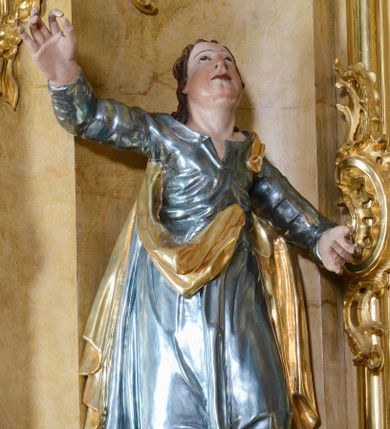 Zdjęcie nr 1: Rzeźba ścięta z tyłu, drążona, ustawiona na półokrągłej podstawie. Figura św. Jana ustawiona frontalnie w kontrapoście, z głową skierowaną ku górze. Prawa ręka uniesiona wysoko; lewa ugięta, odsunięta w bok; dłonie masywne. Twarz owalna, o młodzieńczych rysach i pulchnych policzkach, oczy skierowane ku górze, nos niewielki, usta pełne. Włosy długie, falowane, ściśle przylegają do głowy i opadają na ramiona. Święty jest ubrany w laserunkową, niebieską suknię z długimi rękawami, z rozchylonym dekoltem, ściśle przylegającą do ciała w partii torsu oraz obficie fałdowaną i marszczoną, a u spodu drapowaną w grube fałdy. Ma również złocony płaszcz zawieszony na lewym ramieniu, opadający na plecy i boki z fragmentem tkaniny zawieszonym z przodu. Po prawej stronie figury orzeł. Polichromia w odsłoniętych partiach ciała naturalistyczna, suknia pokryta laserunkiem, płaszcz złocony.