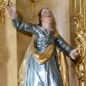 Zdjęcie nr 1: Rzeźba ścięta z tyłu, drążona, ustawiona na półokrągłej podstawie. Figura św. Jana ustawiona frontalnie w kontrapoście, z głową skierowaną ku górze. Prawa ręka uniesiona wysoko; lewa ugięta, odsunięta w bok; dłonie masywne. Twarz owalna, o młodzieńczych rysach i pulchnych policzkach, oczy skierowane ku górze, nos niewielki, usta pełne. Włosy długie, falowane, ściśle przylegają do głowy i opadają na ramiona. Święty jest ubrany w laserunkową, niebieską suknię z długimi rękawami, z rozchylonym dekoltem, ściśle przylegającą do ciała w partii torsu oraz obficie fałdowaną i marszczoną, a u spodu drapowaną w grube fałdy. Ma również złocony płaszcz zawieszony na lewym ramieniu, opadający na plecy i boki z fragmentem tkaniny zawieszonym z przodu. Po prawej stronie figury orzeł. Polichromia w odsłoniętych partiach ciała naturalistyczna, suknia pokryta laserunkiem, płaszcz złocony.