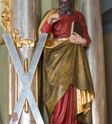 Zdjęcie nr 5: Nastawa ołtarzowa architektoniczna, jednoosiowa, jednokondygnacyjna ze zwieńczeniem i bramkami. Ołtarz drewniany, sarkofagowy, wklęsło-wypukły, zwężający się ku dołowi; dekorowany w narożach ornamentem rocaille&#039;owym, od frontu z rocaille&#039;owym kartuszem. Mensa z portatylem. Tabernakulum w formie zbliżonej do prostopadłościennej skrzynki, ustawione na niskim cokole, o wypukłej ściance frontowej; ujęte drewnianą obudową o wklęsłych bokach, flankowane parą ustawionych pod kątem pilastrów na wysokich cokołach, których trzony przyjmują formę wolut, nad nimi uskrzydlone główki aniołków. Zwieńczenie tabernakulum w formie profilowanego gzymsu, wyłamanego nad osiami bocznymi. Całość ujęta po bokach rocaille&#039;owymi uszami. Część środkowa nowa, miedziana z wypukłymi drzwiczkami w formie stojącego prostokąta zamkniętego łukiem nadwieszonym. W polu aplikowane przedstawienie pelikana karmiącego młode w gnieździe, z krzyżem, gorejącym sercem i arma Christi (włócznia i gąbka z octem) powyżej. Nad drzwiczkami rocaille&#039;owa wstęga. Nastawa ustawiona na zdwojonym cokole, o delikatnie wklęsłym przebiegu, ujęta parą pilastrów od wewnątrz oraz dwiema parami kolumn na skrajach, z których zewnętrzne są cofnięte. Podpory dźwigają pełne belkowanie, wyłamane pośrodku; na linii kolumn cokoły i fragmenty belkowania ustawione pod kątem. Pomiędzy podporami figury: po lewej św. Piotra, a po prawej św. Pawła, przed kolumnami: po lewej św. Jana Ewangelisty, a po prawej św. Andrzeja. Tabernakulum flankuje para rzeźbionych aniołów. W polu środkowym nisza w formie stojącego prostokąta, zamkniętego łukiem nadwieszonym w podwójnej profilowanej, złoconej i od wewnątrz ażurowej ramie z obrazem św. Marcina. Zwieńczenie w formie zbliżonej do leżącego prostokąta ujętego podwójnymi spływami wolutowymi, zamknięte szczytem utworzonym z ornamentu rocaille&#039;owego, po bokach wazony płomieniste. W polu figura Chrystusa Zmartwychwstałego w otoczeniu płaskorzeźbionych obłoków i uskrzydlonych główek anielskich. Na belkowaniu, nad środkową parą kolumn przerwany wolutowy przyczółek z figurami aniołów. Bramki z drzwiczkami w formie stojącego prostokąta, flankowane węgarami, zamknięte wolutowym łukiem z zatkniętym na szczycie wazonem płomienistym, w polu dekorowane rocaille&#039;owymi płycinami. Cokoły i trzony pilastrów dekorowane rocaille&#039;m, w polu między pilastrami, a kolumnami trzy pary kwiatowych zwisów. Nisza pola środkowego zwieńczona rocaille&#039;owym kartuszem. Struktura polichromowana w kolorze seledynowym, profilowania i płyciny w kolorze ciemnoszarym, kapitele i rama obrazu w kolorze czerwonym, ornamentyka złocona, kolumny i obłoki srebrzone.