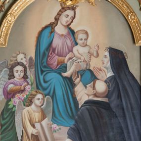 Zdjęcie nr 1: Obraz w kształcie stojącego prostokąta zamkniętego łukiem nadwieszonym przedstawia Matkę Boską przekazującą różańce św. Dominikowi oraz św. Katarzynie ze Sieny. Matka Boska ukazana w górnej, lewej partii obrazu w pozycji siedzącej na tronie z Dzieciątkiem Jezus na kolanach. Maria zwrócona trzy czwarte w lewo, prawą ręką przekazuje różaniec św. Dominkowi, lewą przytrzymuje Dzieciątko. Twarz owalna, z małymi ustami, długim i wąskim nosem, oczami lekko przymkniętymi; włosy długie, opadające na ramiona i plecy. Ubrana jest w długą, różową suknię z długimi rękawami i ciemnoniebieski płaszcz nałożony na ramiona. Dzieciątko Jezus zwrócone trzy czwarte w prawo, z głową skierowaną delikatnie w lewo, lewą rączką czyni znak błogosławieństwa, prawą przekazuje różaniec św. Dominikowi. Ubrane jest w krótką pieluszkę przewiązaną wokół bioder. Wokół głów Maryi i Dzieciątka złote, świetliste nimby; na głowie Matki Boskiej korona otwarta. W dolnej, prawej partii obrazu ukazani święci: Dominik i Katarzyna, w pozycji klęczącej, widoczni z lewego profilu, zwróceni w kierunku Matki Boskiej. Święta Katarzyna z rękoma złożonymi w geście modlitwy, św. Dominik prawą ręką odbiera różaniec, lewą trzyma opuszczoną w dół. Święci są ubrani w habity i płaszcze dominikańskie, nad głowami okrągłe nimby z gwiazdą w polu, na głowie św. Katarzyny korona cierniowa. Po lewej stronie obrazu trójka aniołów, ustawionych jeden za drugim, pierwszy w pozycji klęczącej z otwartą księgą w dłoniach. Poniżej pies z pochodnią w pysku oraz gałązka róży. Tło w górnej części obrazu szare, rozświetlone wokół postaci Matki Boskiej i Dzieciątka. Rama złocona, profilowana, pośrodku zdobiona motywem karbowania oraz pojedynczymi rzeźbionymi kwiatami słoneczników, a u góry z rocaille&#039;owym kartuszem.