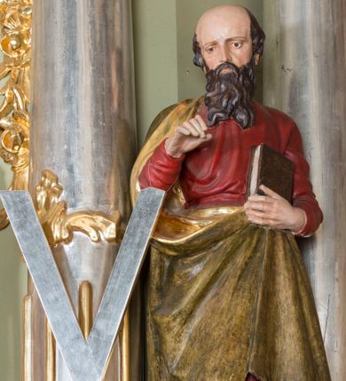 Zdjęcie nr 1: Rzeźba św. Andrzeja ścięta z tyłu, ustawiona na niskim, prostopadłościennym cokole o ściętych narożach. Figura zwrócona frontalnie, z prawą nogą delikatnie ugiętą w kolanie, z pochyloną głową. Lewą ręką przytrzymuje przy piersi zamkniętą księgę; prawą również ugiętą, unosi przed siebie. Twarz o wysokim czole, z wyraźnie zaznaczoną łysiną okolona długą, falującą brodą, rozdzieloną na końcu na dwa pukle, nos długi i wąski, oczy skierowane w dół. Włosy średniej długości, widoczne po bokach głowy. Święty jest ubrany w czerwoną suknię z długimi rękawami oraz  płaszcz w kolorze brudnozłotym ze złoconą podszewką, zawieszony na prawym ramieniu i podtrzymywany z przodu, drapowany w grube, miękkie fałdy. Obok rzeźby, po lewej stronie stoi wysoki, srebrzony krzyż w kształcie litery „X”. Polichromia w odsłoniętych partiach ciała naturalistyczna, podszewka płaszcza złocona, krzyż srebrzony.