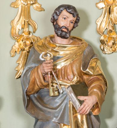 Zdjęcie nr 1: Rzeźba ścięta z tyłu, ustawiona na prostokątnej podstawie o ściętych przednich narożach. Figura ustawiona frontalnie, w postawie stojącej z dwoma kluczami w prawej dłoni i zamkniętą księgą w lewej, z głową delikatnie przechyloną w lewo. Twarz pociągła, okolona średniej długości brodą, nos długi i wąski, oczy skierowane w dal, włosy średniej długości, falowane, zasłaniające uszy. Święty ubrany jest w długą, brązową suknię z długimi rękawami oraz srebrny płaszcz ze złotą podszewką. Polichromia  w odsłoniętych partiach ciała naturalistyczna, podbicie płaszcza i detale złocone i srebrzone.