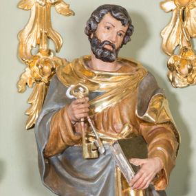 Zdjęcie nr 1: Rzeźba ścięta z tyłu, ustawiona na prostokątnej podstawie o ściętych przednich narożach. Figura ustawiona frontalnie, w postawie stojącej z dwoma kluczami w prawej dłoni i zamkniętą księgą w lewej, z głową delikatnie przechyloną w lewo. Twarz pociągła, okolona średniej długości brodą, nos długi i wąski, oczy skierowane w dal, włosy średniej długości, falowane, zasłaniające uszy. Święty ubrany jest w długą, brązową suknię z długimi rękawami oraz srebrny płaszcz ze złotą podszewką. Polichromia  w odsłoniętych partiach ciała naturalistyczna, podbicie płaszcza i detale złocone i srebrzone.