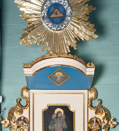 Zdjęcie nr 3: Ambona wisząca, przyścienna, złożona z kosza i schodów z balustradą, zaplecka i baldachimu ze zwieńczeniem. Kosz na planie kwadratu z wypukłą ścianą frontową, ujęty jednym pilastrem przy ścianie bocznej. Na ścianach płyciny o wykroju kwadratu z wklęsłymi narożami, wewnątrz rozety. Kosz zakończony profilowanym gzymsem, od dołu otoczony pasem z dekoracją w formie nacięć. Spięty u dołu szyszką z fryzem zdobionym czterema wolutami oraz pierścieniem z dekoracją w formie łezek. Od wschodu schody jednobiegowe z balustradą zdobioną płycinami z rozetami oraz profilowaną poręczą. Pulpit w kształcie kwadratu zamkniętego łukiem odcinkowym nadwieszonym. Zaplecek w formie stojącego prostokąta, ujęty uszami utworzonymi z ornamentu rocaille’owego połączonego z wicią i rozetami, z umieszczonymi w strukturze płaskorzeźbami postaci w niszach zamkniętych łukiem półokrągłym i wypełnionych muszlą; po lewej Jezus z barankiem, po prawej św. Kazimierz (?). Pośrodku pole obrazowe o wykroju stojącego prostokąta z wklęsłymi narożami, w nim obraz Chrystusa Dobrego Pasterza. Baldachim w formie prostokąta zamkniętego od zewnętrznej strony łukiem odcinkowym nadwieszonym; podniebie malowane na niebiesko, pośrodku pole obrazowe w formie rombu, wypełnione przedstawieniem gołębicy Ducha Świętego. Ponad baldachimem duża gloria promienista, w centrum której wizerunek Oka Opatrzności.