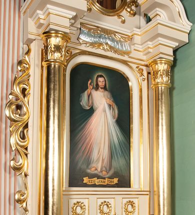 Zdjęcie nr 2: Ołtarz architektoniczny, przyścienny, jednoosiowy, jednokondygnacyjny ze zwieńczeniem. Nastawa umieszczona jest na skrzyniowej mensie z kamiennym blatem. Antepedium ozdabia okrągła płycina z czteroliściem wpisanym w koło, flankowana przez dwie kwadratowe płyciny, których wewnętrzne krawędzie są wklęsłe. Boczne ścianki mensy ozdobione są prostokątną płyciną. Nastawa flankowana ustawionymi na wysuniętych partiach cokołu kolumnami dźwigającymi pełne belkowanie wyłamane na ich osiach i podtrzymujące fragmenty urwanego przyczółka. Cokół jest dekorowany prostokątnymi płycinami, na osiach zewnętrznych dodatkowo wypełnionymi ornamentem małżowinowym i rocaille’owym. W polu centralnym nisza zamknięta od góry łukiem spłaszczonym, w której na tle złoconego tła umieszczono krucyfiks przesłaniany wizerunkiem „Jezu Ufam Tobie”. Poniżej niszy trzy płyciny z symetryczną dekoracją rocaille’ową, powyżej wstęga z napisem „OJCZĘ ODPUS NAM” ujęta liśćmi. Kondygnacja jest z lewej strony ujęta uszakiem skomponowanym z ażurowej wici akantowej. Pole zwieńczenia wypełnia rama w kształcie stojącego owalu z wizerunkiem św. Teresy od Dzieciątka Jezus otoczona ornamentem inspirowanym małżowinowym. Powyżej muszla palmetowa, na urwanych fragmentach przyczółka posadowiono anioły. 
Struktura polichromowana na kremowo ze złoconą i srebrzoną ornamentyką oraz detalami architektonicznymi. 